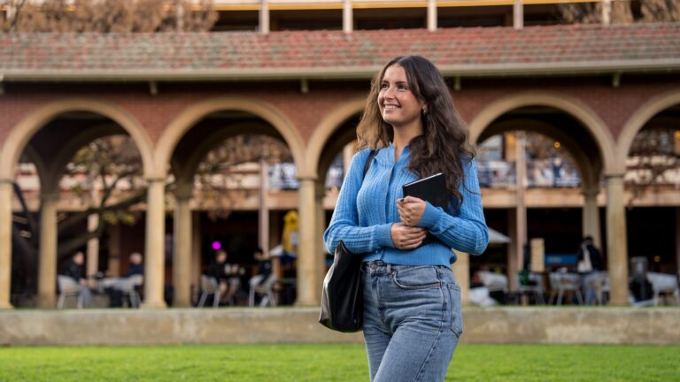 A student walking beneath the cloisters at Adelaide University