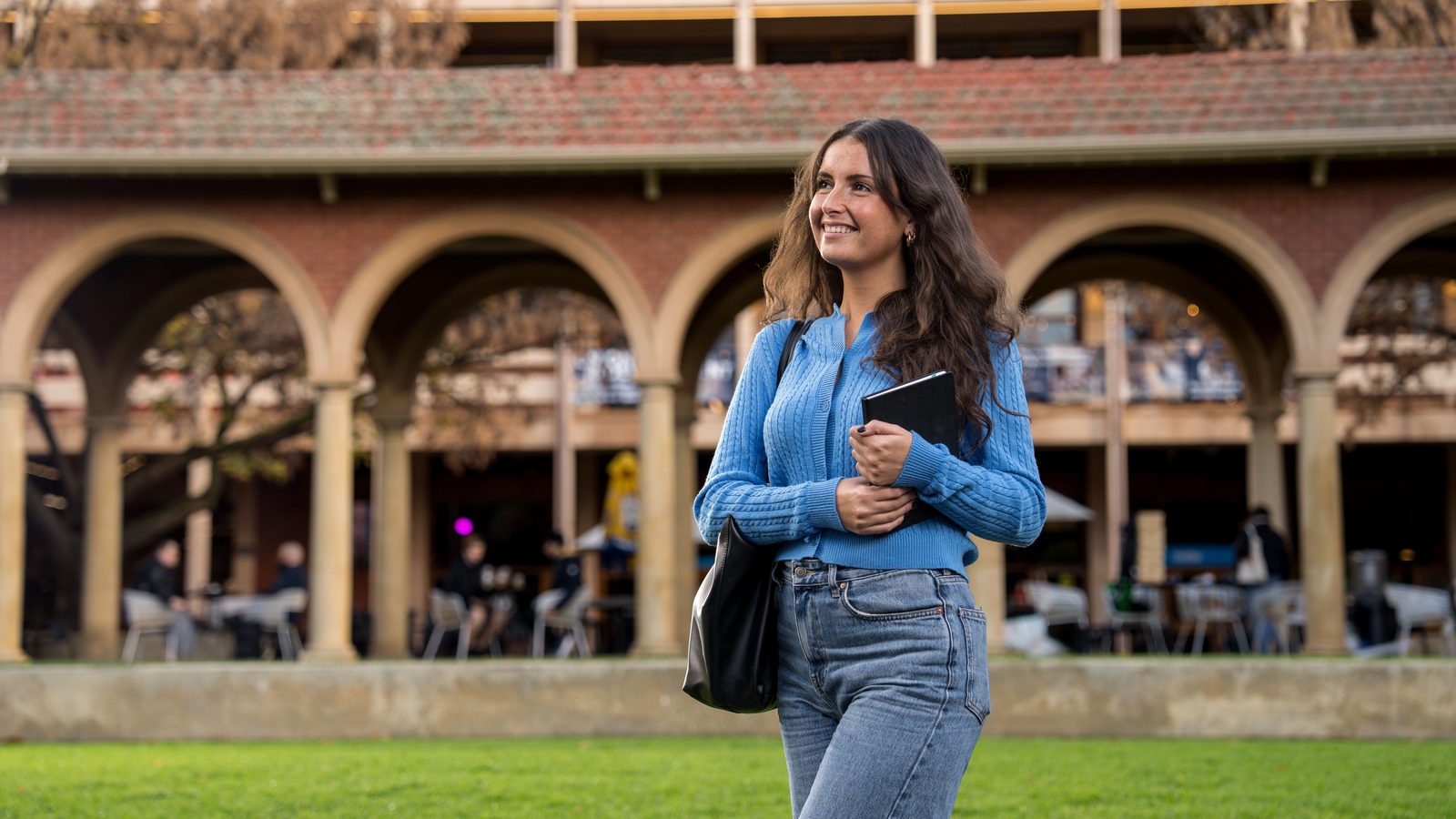 A student walking beneath the cloisters at Adelaide University