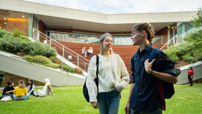 Two students talking beside a campus lawn at Adelaide University