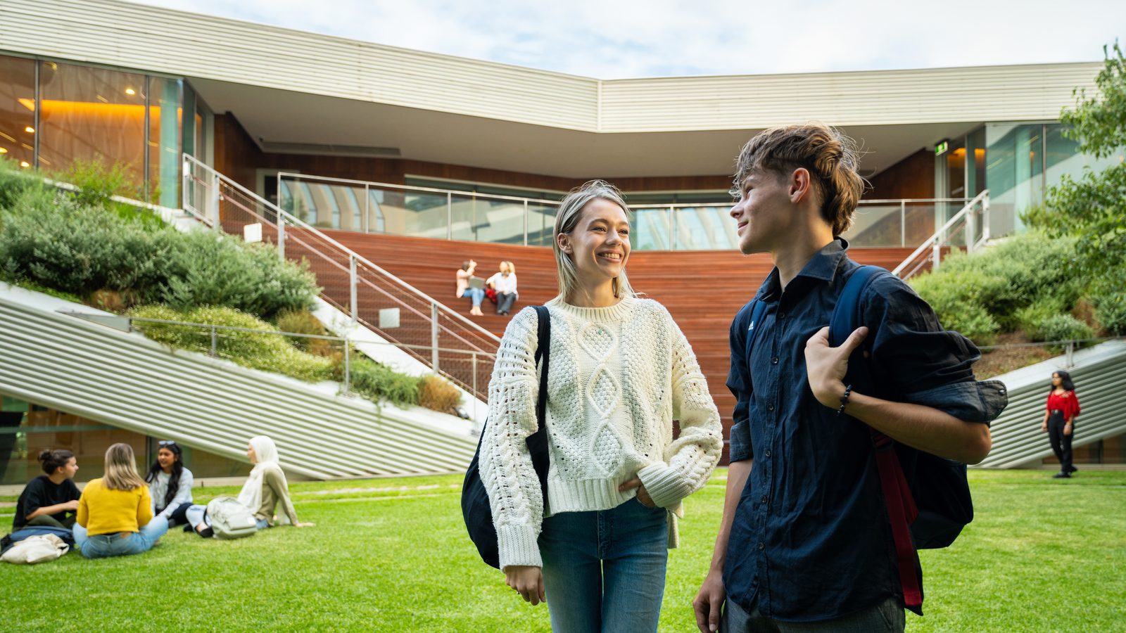 Two students talking beside a campus lawn at Adelaide University
