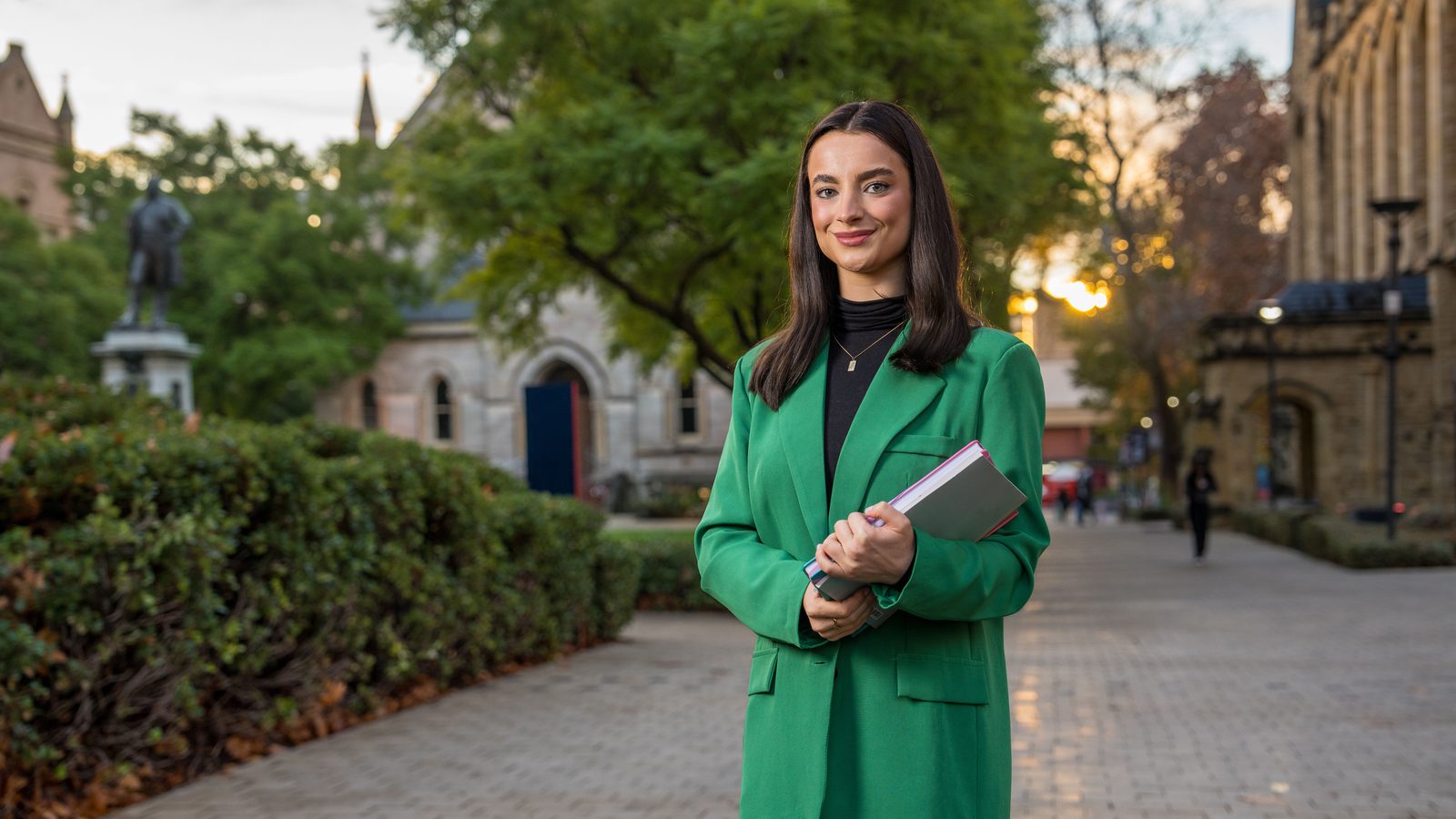 A student holding a notebook on the Adelaide University campus
